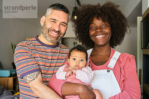 Portrait of a multiracial family with a baby at home.