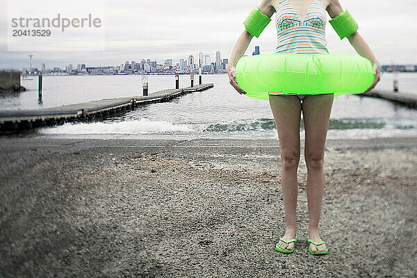 A woman stands at a boat launch. The Seattle skyline is behind her.