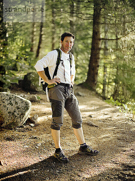 A portrait of a middle aged man standing on a trail.