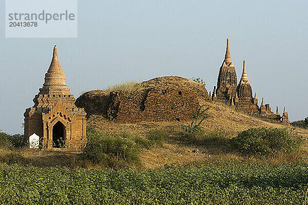 A group of 13th-century pagodas of varying sizes stand among farm fields lining the shores of the Irrawaddy river at Bagan  Union of Myanmar (Burma)