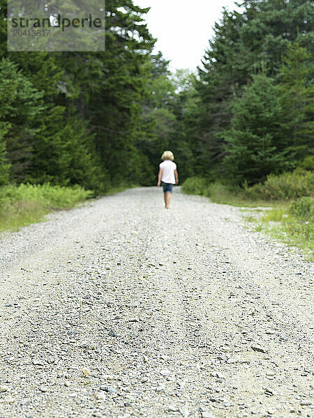 young girl walks down dirt road on maine island