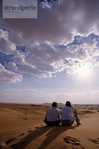 Two people sitting in the sand  Dubai  United Arab Emirates.