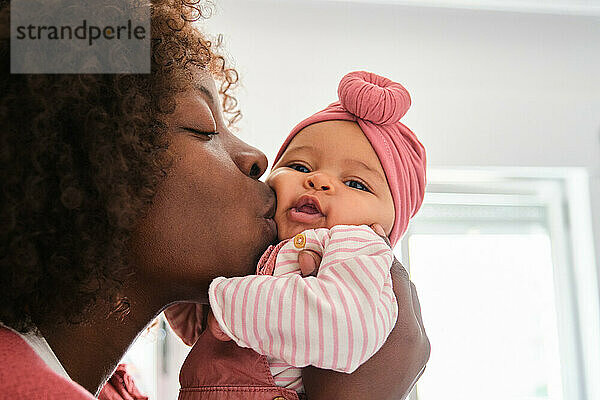 African woman is kissing her baby girl.