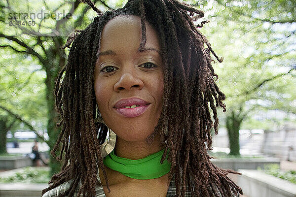 Portrait of a young woman with hair in dreads  in a city park.