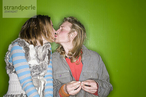 Young couple kissing against a green background.