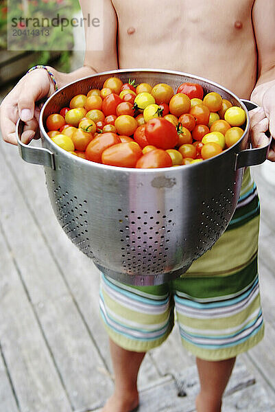 boy proudly shows off his tomato harvest