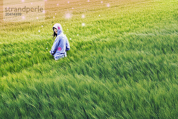 A young woman stands in a field  Berg  Switzerland.