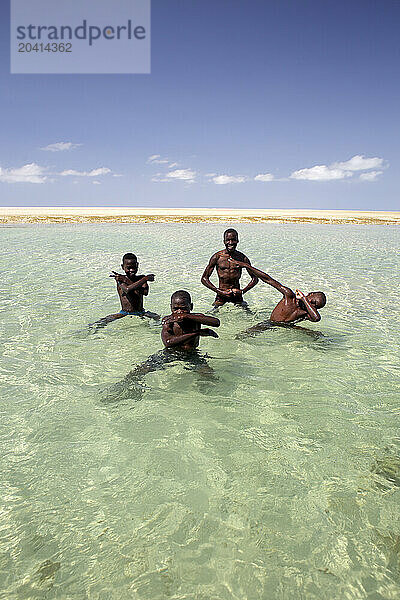 Four boys posing together in coastal water  Mozambique