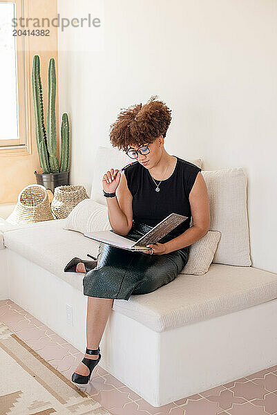 Women with afro sitting on couch writing in note book