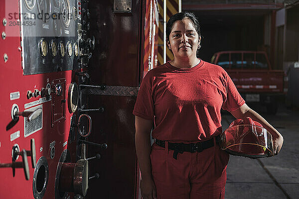 Portrait of female firefighter standing at fire station