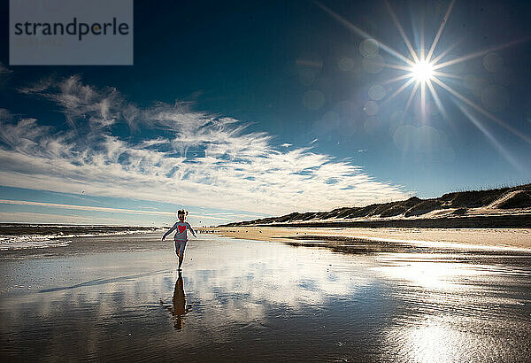 Young child running down beach on sunny day