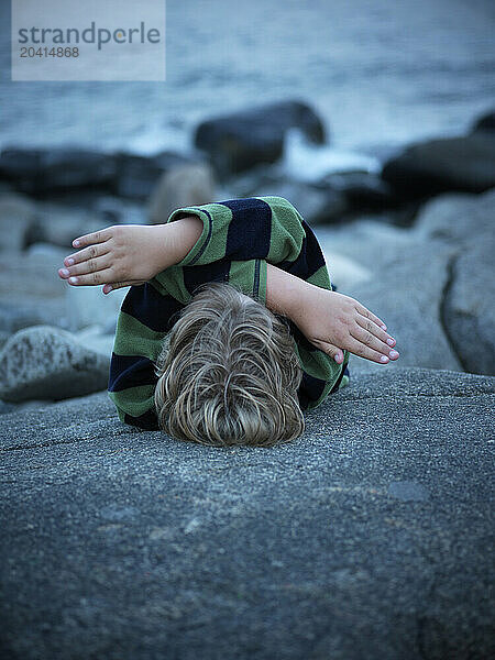 boy lies on rock on maine coast