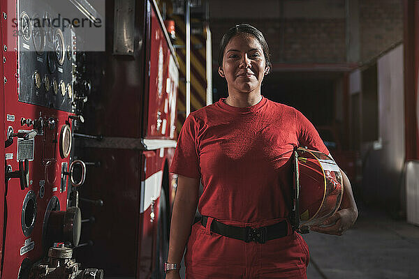 Portrait of female firefighter standing at fire station