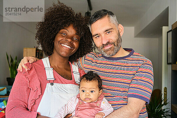 Portrait of a multiracial family with a baby at home.