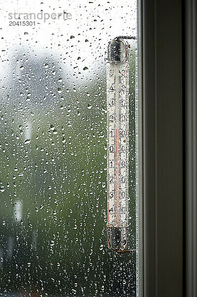 Rain seen through a window with a thermometer showing 15 degrees.