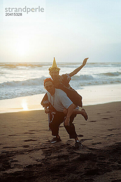 Happy friends fooling around on the beach at a party.