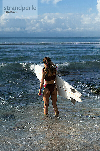 Young woman with surfboard on a beach.