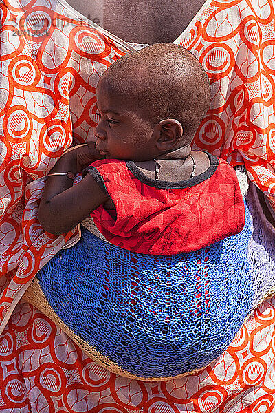 African bedik woman carrying a child while doing housework  ziguinchor  casamance  Senegal  Africa