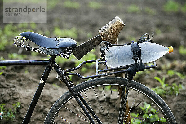 Field worker's bike with water bottle and axe.