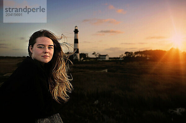 Portrait of beautiful girl with lighthouse and sunset