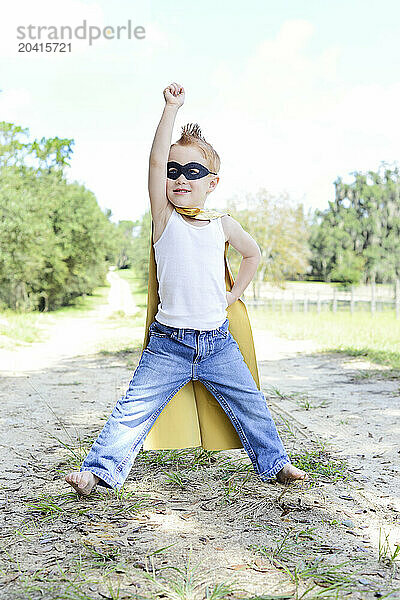 Confident toddler in superhero costume striking a pose outdoors.