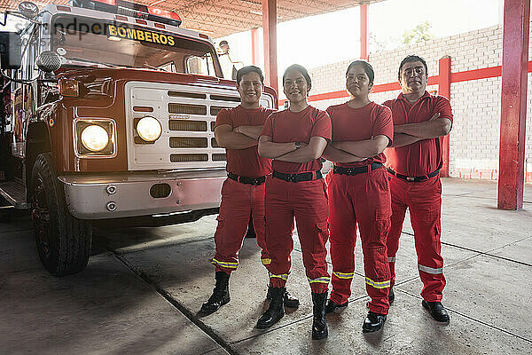 Portrait of a team of male and female firefighters with fire truck