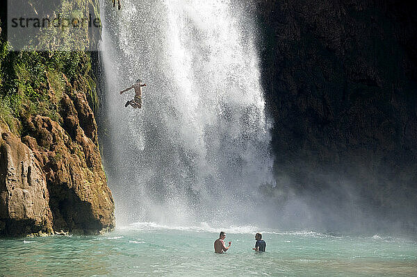 A man jumping into a waterfall at Havasu Falls  Grand Canyon Arizona