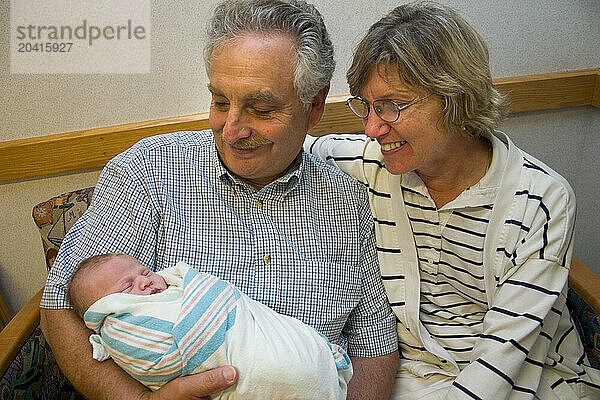 Grandparents holding a newborn baby in the hospital