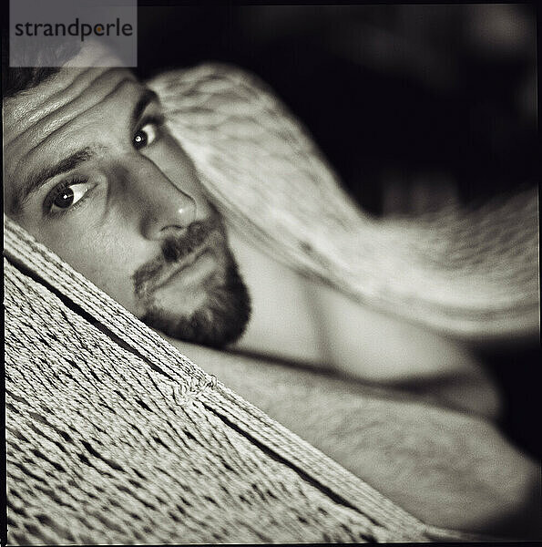 A young man looks out as he lays in a hammock  Troncones  Mexico