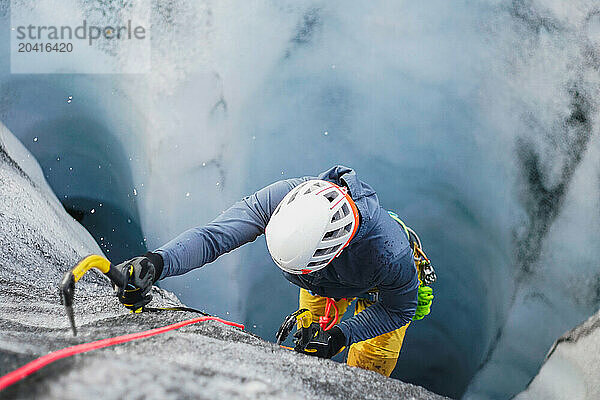 Man ice climbing up a glacier crevasse on an Icelandic glacier