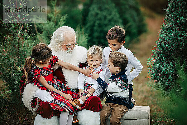 Santa with four kids in festive attire at a Christmas tree farm