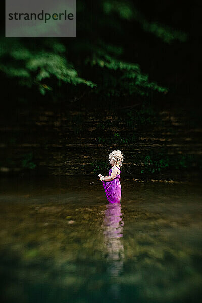 Young girl standing in scenic creek during summer