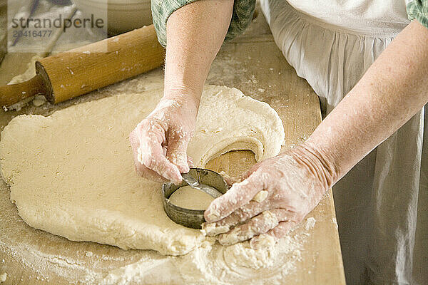 Woman cutting biscuits from prepared dough.