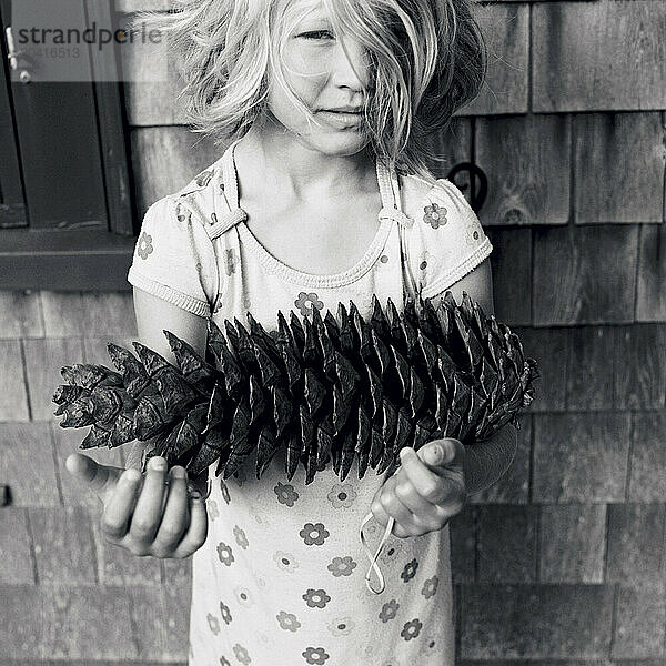 young girl with large pine cone