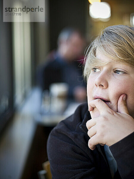 boy in a cafe gazes out window