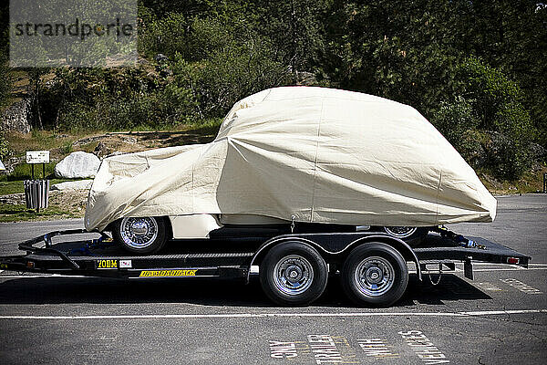 A classic car covered in a sheet on a trailer near Tubbs Hill in Coeur D'Alene  Idaho.