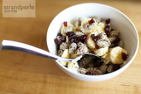 A top down view of a healthy breakfast bowl of cranberries  almonds  Greek yogurt and bananas.