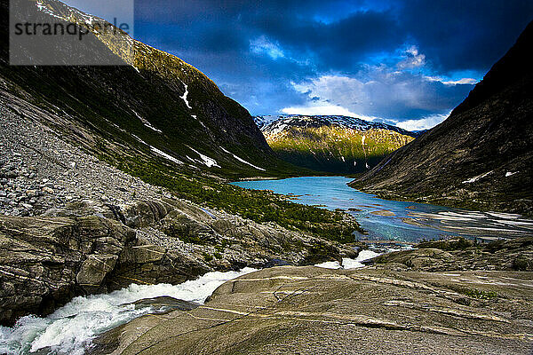 A waterfall meets the blue waters of a fjord in Jostedal Glacier National Park in Norway.