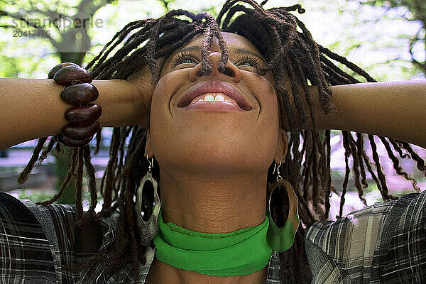 Portrait of a young woman with hair in dreads  in a city park.