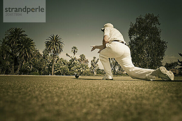 A older man outside lawn bowling.