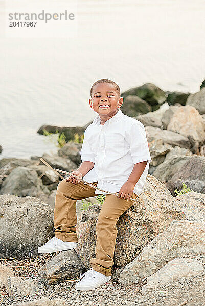 Boy sitting on a rock smiling at the camera