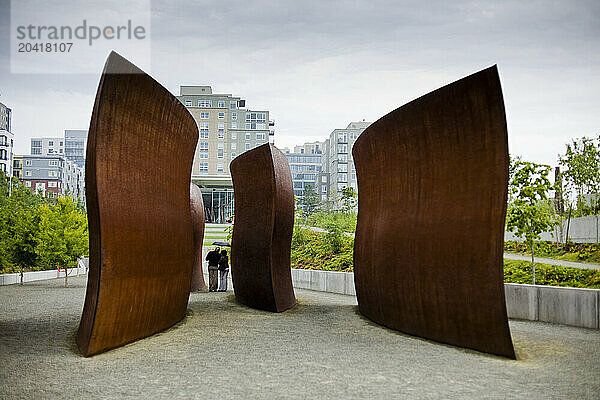 A young couple walks past Richard Serra's sculpture 'Wake ' in the Olympic Sculpture Park in Seattle WA.