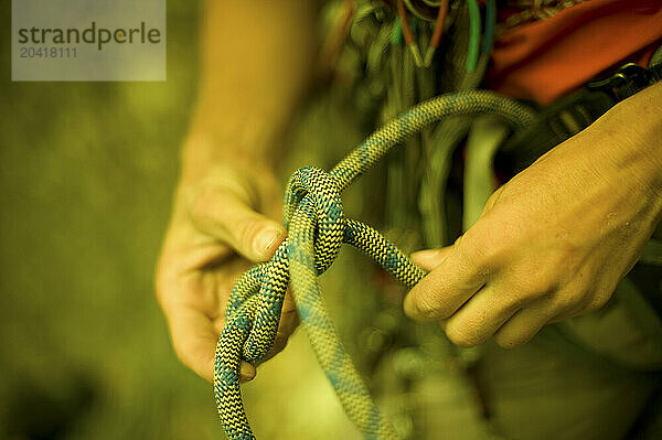 A woman about to climb ties a figure 8 knot.