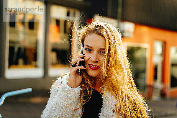 Smiling woman using mobile phone on the street.