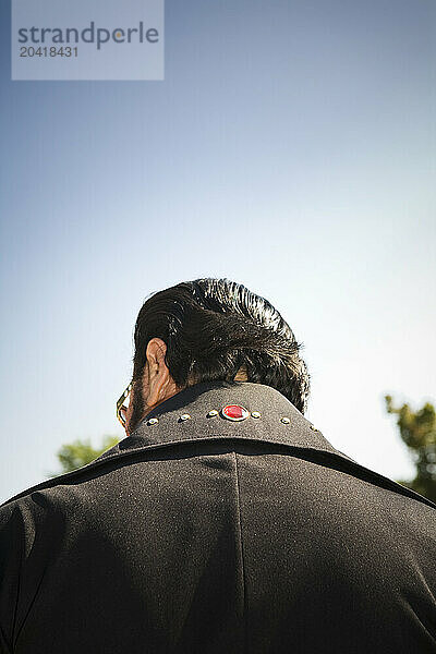 Rear view of an Elvis impersonator in a black suit.