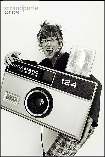 A young woman pretends to take pictures with a giant camera