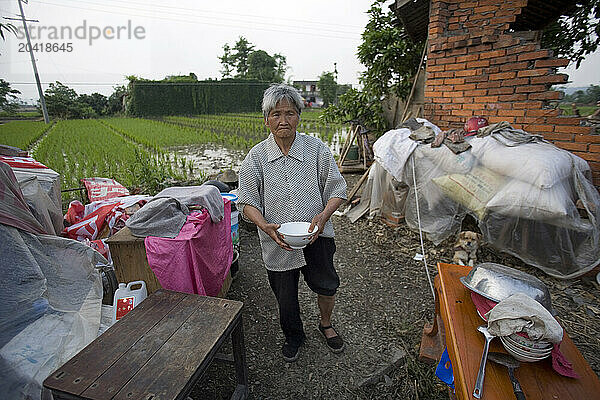 A woman holds bowls she salvaged after an earthquake in Sichuan  China.