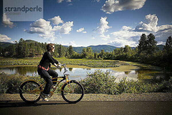 A young woman rides a bike in the countryside  on the Rails to Trails system through the Couer D'Alene valley  Coeur D'Alene ID.