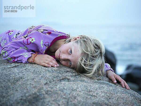 girl lies on rock on maine coast