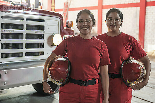 Portrait of happy female firefighters standing at fire station